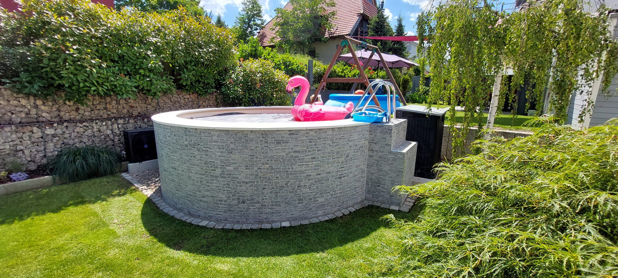 Gepflasterte Hofeinfahrt mit Natursteinmauer und Baumeinfassung
